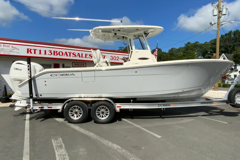 The Image of 2026 Cobia 265 Open Center Console boat on trailer at dealership. - 1