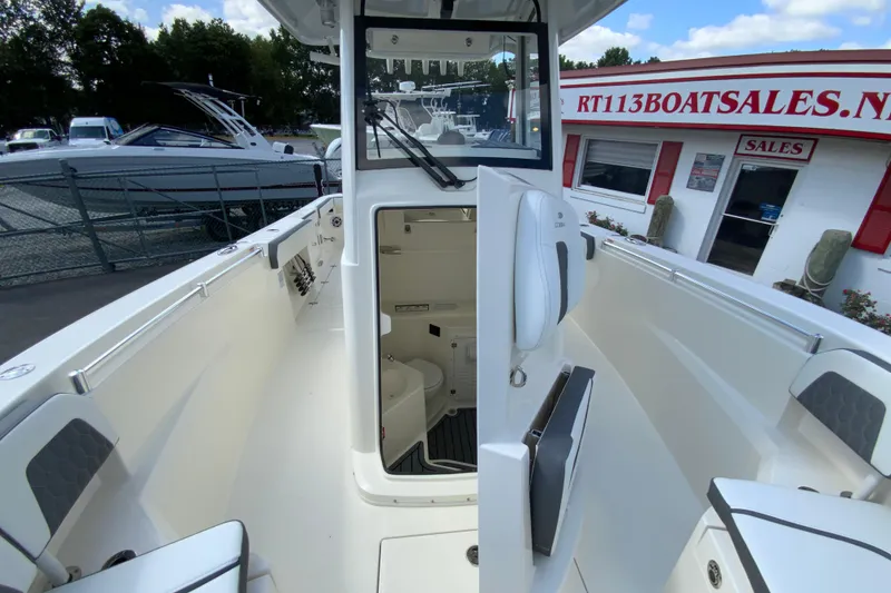 Slide: The Image of 2026 Cobia 265 Open Center Console boat interior at dealership, showcasing seating and storage. - 33