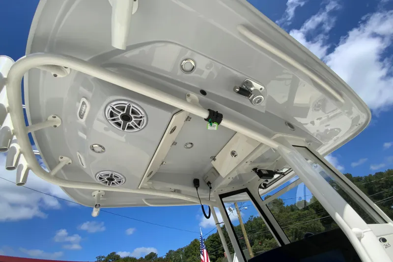 Slide: The Image of 2026 Cobia 265 Open Center Console boat with speakers and rod holders under blue sky. - 38