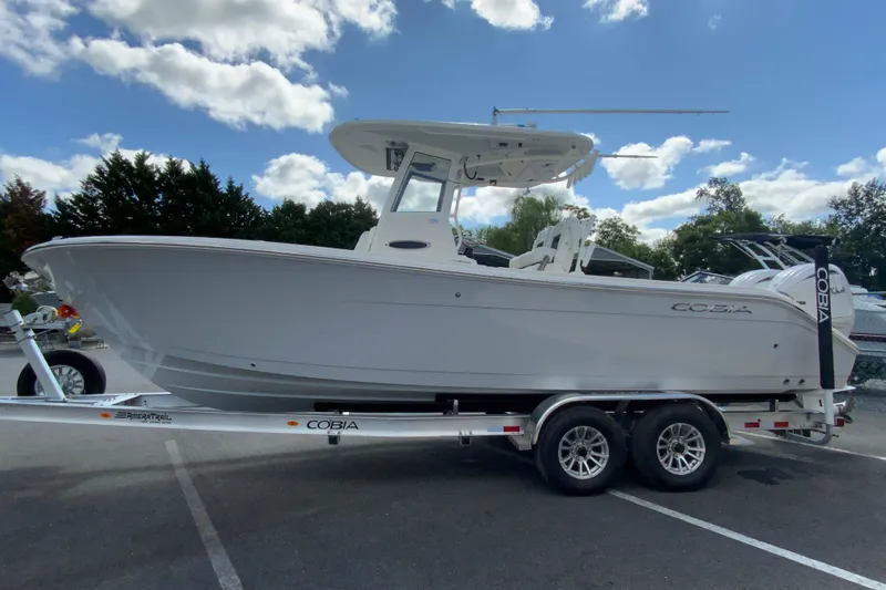 Slide: The Image of 2026 Cobia 265 Open Center Console boat on trailer under blue sky. - 6