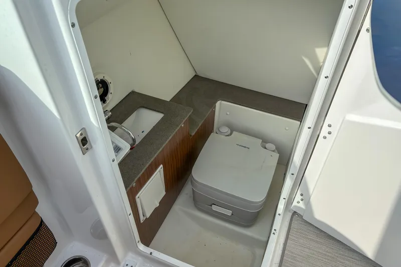 Slide: The Image of 2022 Four Winns HD5 boat interior with compact bathroom and portable toilet. - 5