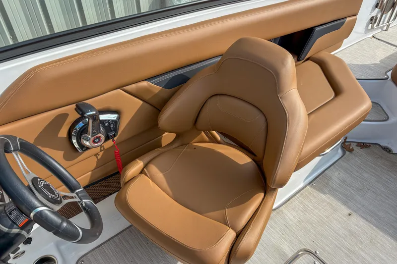 Slide: The Image of 2022 Four Winns HD5 boat interior with tan leather seat and steering controls. - 7