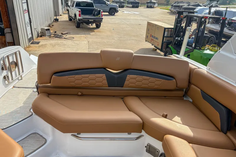 Slide: The Image of 2022 Four Winns HD5 boat interior with tan leather seating, docked near vehicles and equipment. - 9