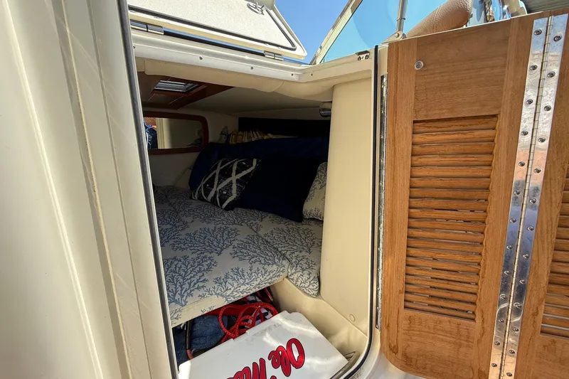 Slide: The Image of 2019 Chris-Craft Corsair 27 cabin interior with bedding and wooden door. - 13