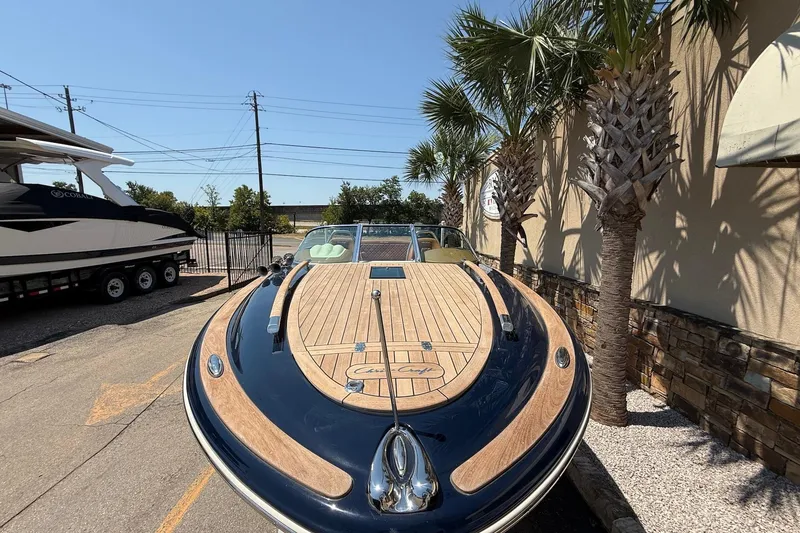 Slide: The Image of 2019 Chris-Craft Corsair 27 boat with wooden deck, parked near palm trees. - 2