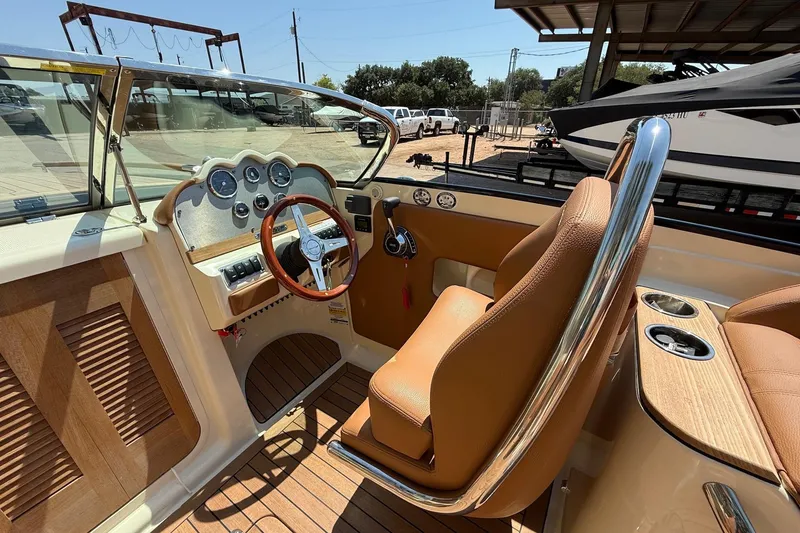 Slide: The Image of 2019 Chris-Craft Corsair 27 boat interior with tan leather seats and wooden dashboard. - 8