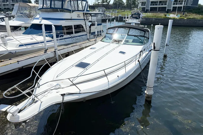 Slide: The Image of 1998 Sea Ray 400 Express Cruiser docked at marina, surrounded by water and other boats. - 0