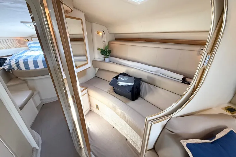 Slide: The Image of 1998 Sea Ray 400 Express Cruiser interior with beige seating and striped bedding. - 18