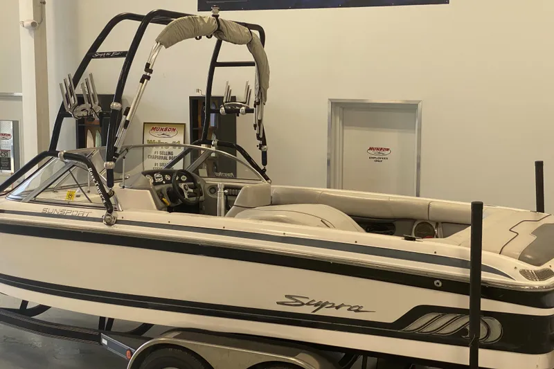 The Image of 2002 Supra Sunsport 22' boat displayed indoors, featuring a sleek design and wakeboard tower. - 0