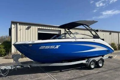 Slide: The Image of 2025 Yamaha Boats 255XD in blue on trailer, parked outside a building. - 3