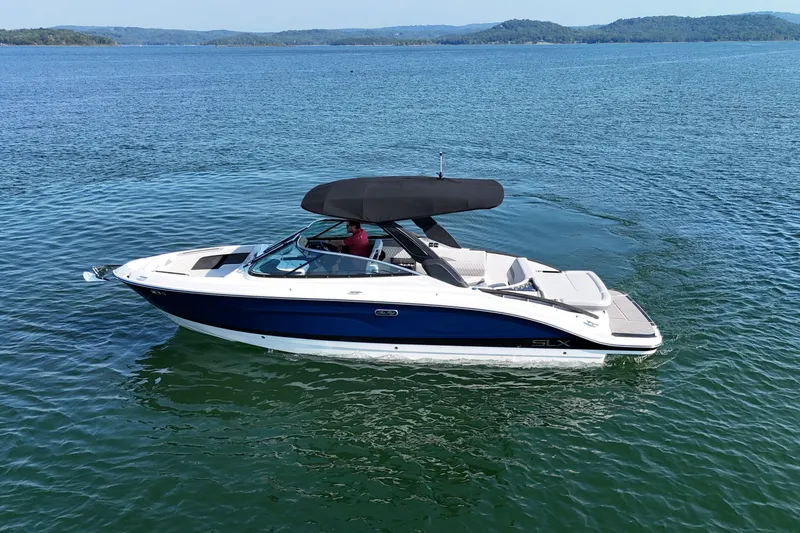 Slide: The Image of 2024 Sea Ray SLX 280 boat cruising on a serene lake with distant hills. - 3