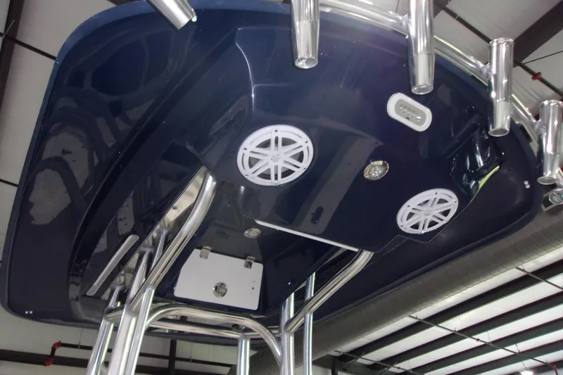 Slide: The Image of 2024 Pathfinder 2200 boat T-top with speakers and rod holders in a warehouse setting. - 16