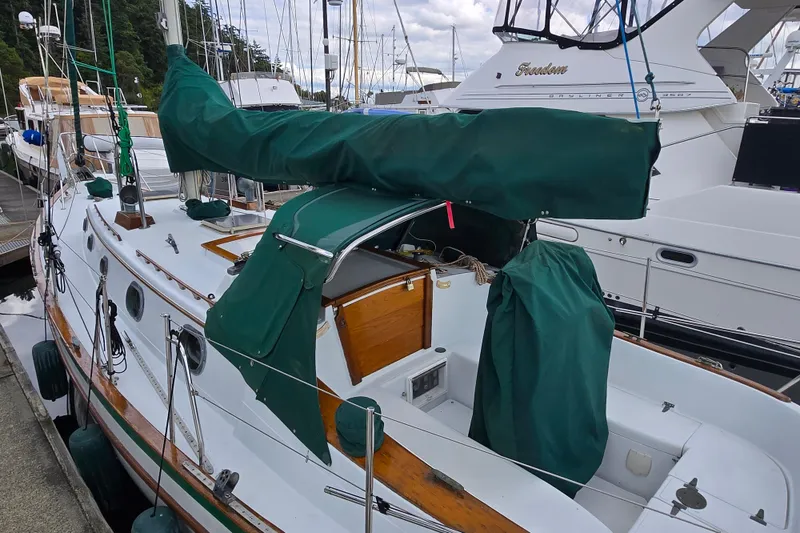 Slide: The Image of 1985 Pacific Seacraft 37 sailboat docked, featuring green covers and wooden accents. - 15