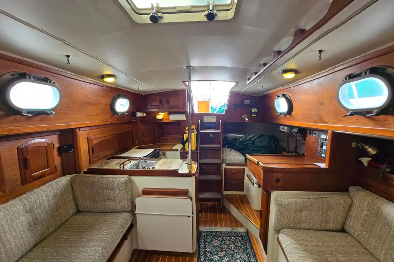 Slide: The Image of Interior of 1985 Pacific Seacraft 37 sailboat, featuring cozy wooden furnishings and porthole windows. - 6