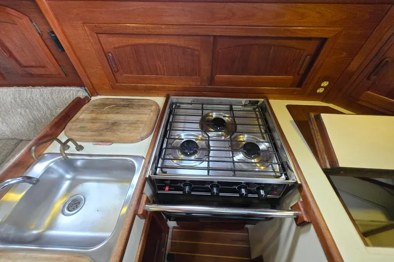 Slide: The Image of 1985 Pacific Seacraft 37 yacht kitchen with stove, sink, and wooden cabinetry. - 9