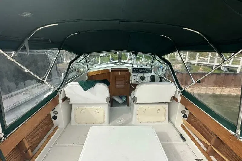 Slide: The Image of 1997 Limestone 24 Cuddy boat interior with seating and steering wheel, docked by the water. - 10