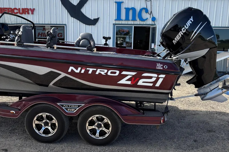Slide: The Image of 2021 Tracker Nitro ZV21 boat with Mercury engine, parked outside a building. - 1