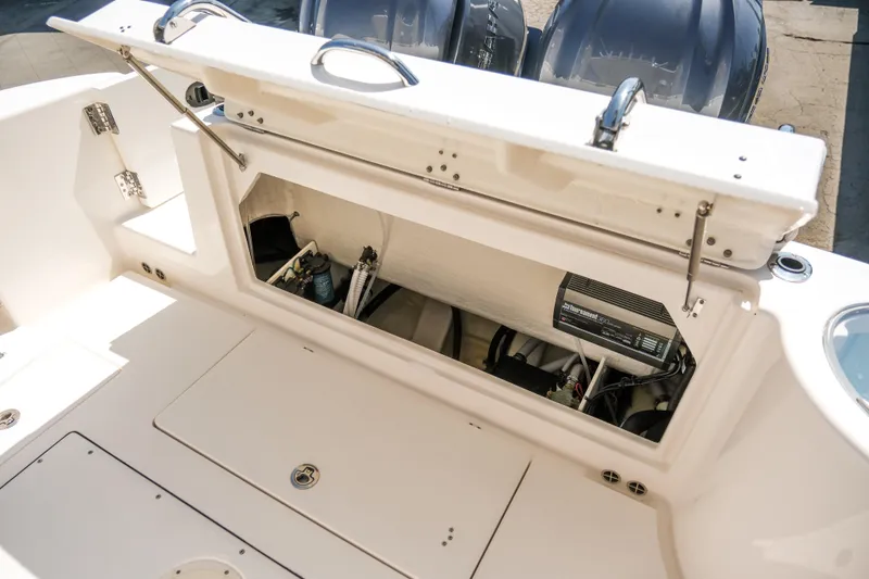 Slide: The Image of 2023 Robalo R302 Center Console boat storage compartment with open hatch and visible equipment. - 32
