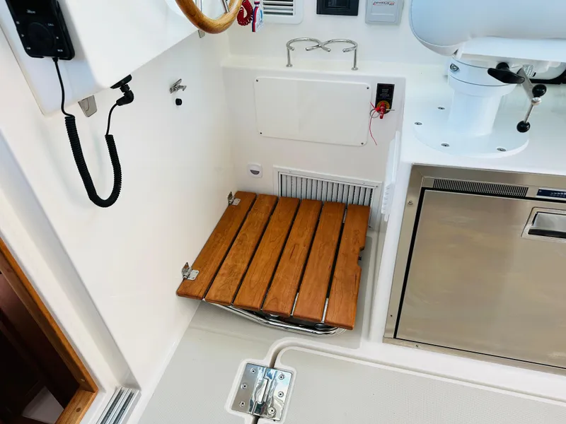 Slide: The Image of 2021 Back Cove 34O interior with wooden foldable seat and stainless steel appliances. - 14