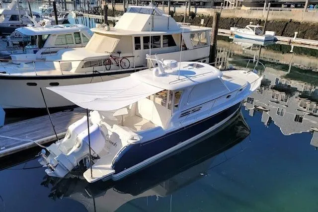 Slide: The Image of 2021 Back Cove 34O boat docked in a marina, featuring a sleek design and sunshade. - 2