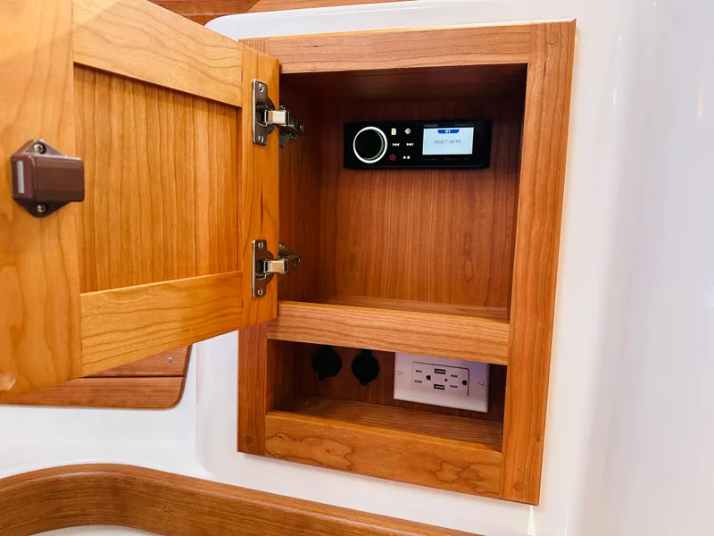 Slide: The Image of Wooden cabinet with open door, revealing a stereo system and electrical outlets on a 2021 Back Cove 34O. - 22