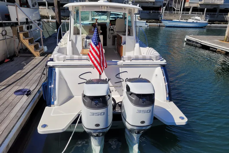 Slide: The Image of 2021 Back Cove 34O boat with dual Suzuki 350 engines, docked with American flag. - 4