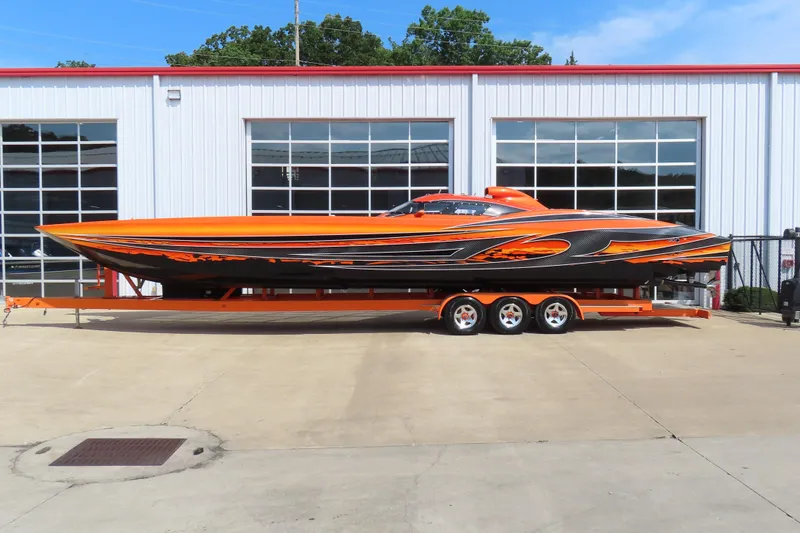 The Image of Orange and black 2005 MTI 44 speedboat on trailer outside garage. - 1