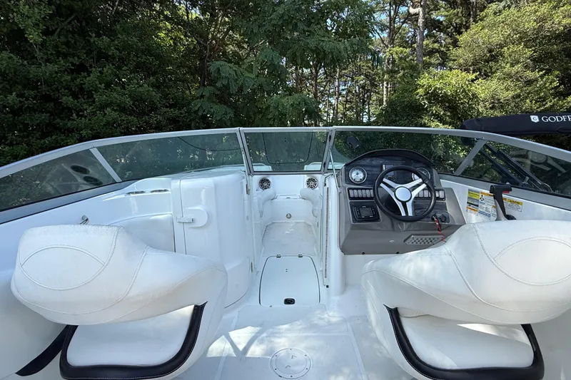 Slide: The Image of 2016 Hurricane SunDeck 2200 DC OB boat interior with steering wheel and white seating. - 11