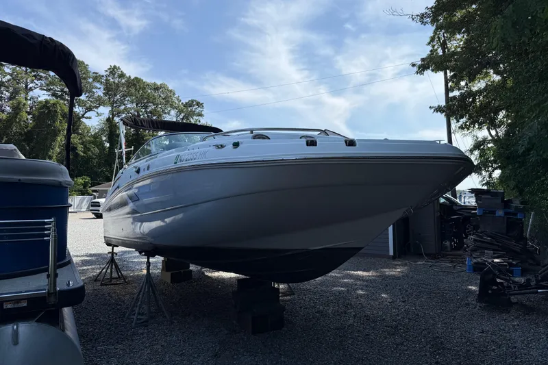 Slide: The Image of 2016 Hurricane SunDeck 2200 DC OB boat on stands, surrounded by trees and other boats. - 2