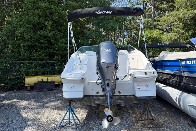 Slide: The Image of 2016 Hurricane SunDeck 2200 DC OB boat with outboard motor on stands, surrounded by trees. - 6