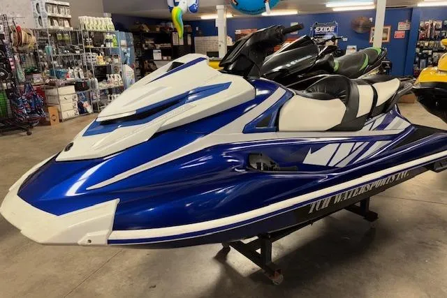 Slide: The Image of 2018 Yamaha WaveRunner GP1800 in showroom, blue and white design, displayed indoors. - 2