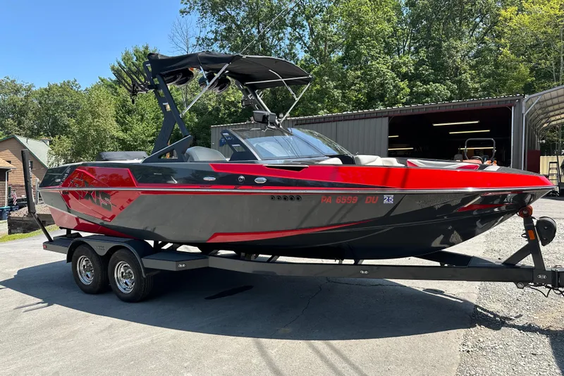 Slide: The Image of 2018 Axis T22 boat in red and black on a trailer, parked outdoors. - 2