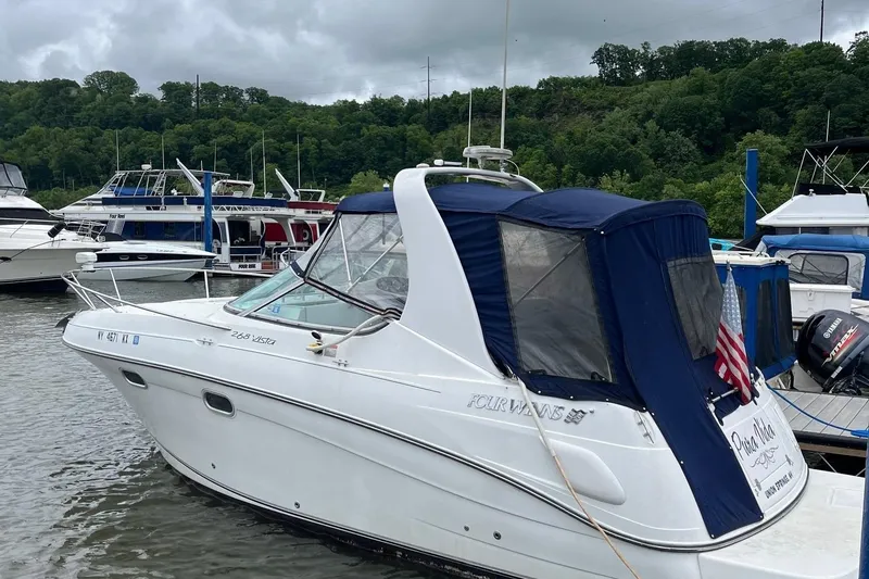 The Image of 2002 Four Winns 268 Vista boat docked, featuring a blue canopy and American flag. - 0