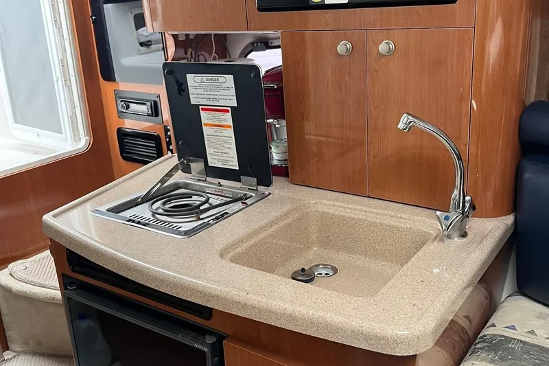 Slide: The Image of 2002 Four Winns 268 Vista boat kitchen with sink, stove, and wooden cabinetry. - 13