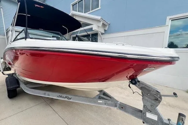 The Image of 2018 Sea Ray 19 SPX OB boat with red hull on trailer, parked outdoors. - 0
