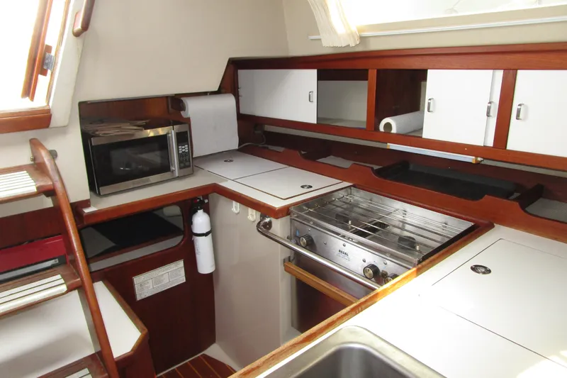 Slide: The Image of 1989 Catalina 36 yacht kitchen with stove, microwave, and wooden cabinetry. - 17