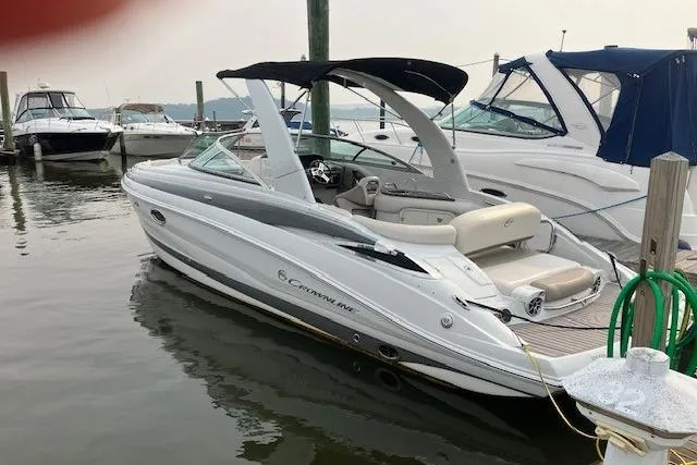 Slide: The Image of 2018 Crownline 285 SS boat docked at marina, featuring sleek design and spacious seating. - 2