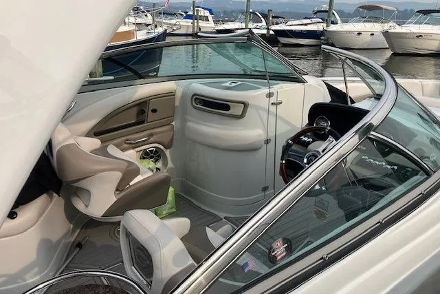 Slide: The Image of 2018 Crownline 285 SS boat interior with helm, seating, and docked boats in background. - 5