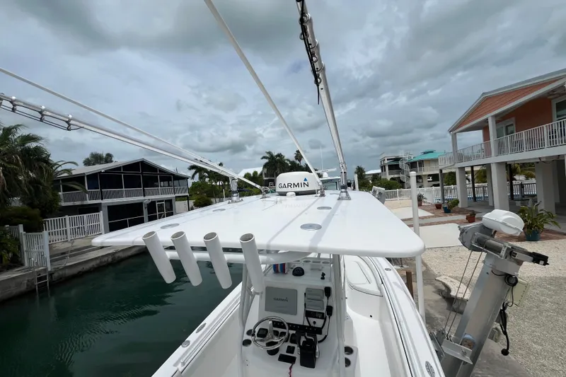 Slide: The Image of 2015 Contender 24 Sport boat docked near waterfront homes under cloudy skies. - 12