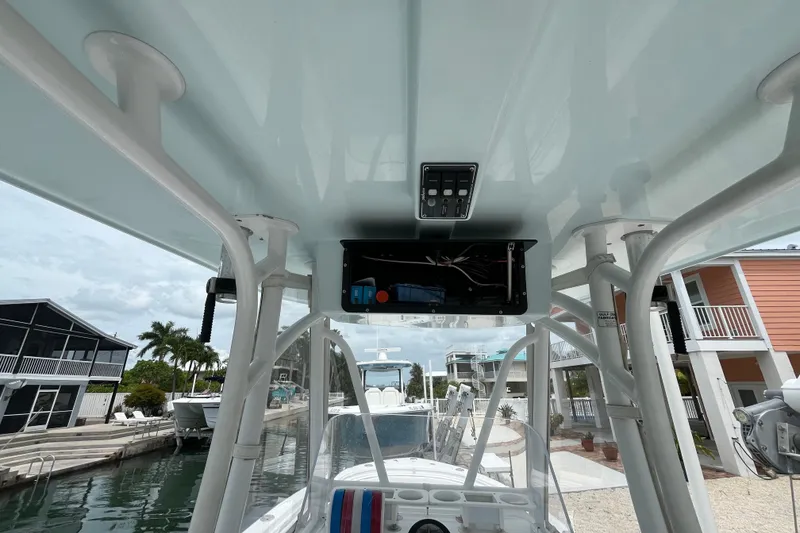 Slide: The Image of 2015 Contender 24 Sport boat interior with T-top and control panel, docked near waterfront homes. - 9