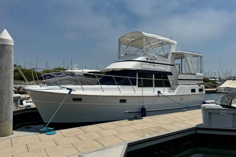 The Image of 1999 Heritage East Sundeck 36 yacht docked at marina under clear sky. - 0