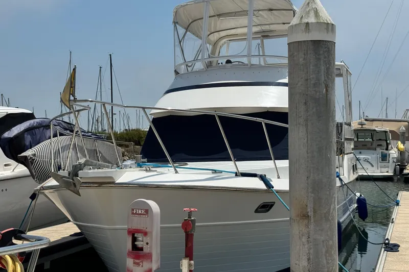 Slide: The Image of 1999 Heritage East Sundeck 36 yacht docked at marina, featuring a covered upper deck. - 1