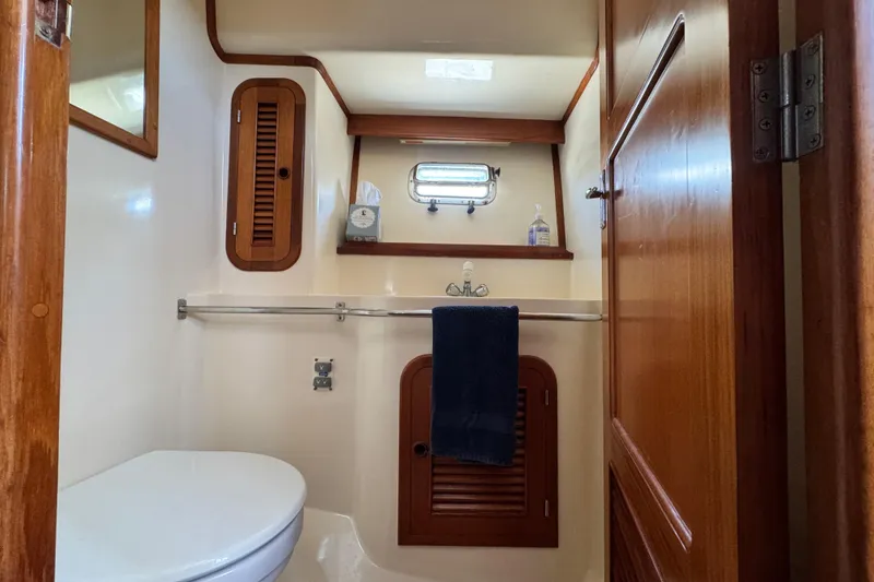 Slide: The Image of 1999 Heritage East Sundeck 36 yacht bathroom with wooden cabinetry and porthole window. - 22