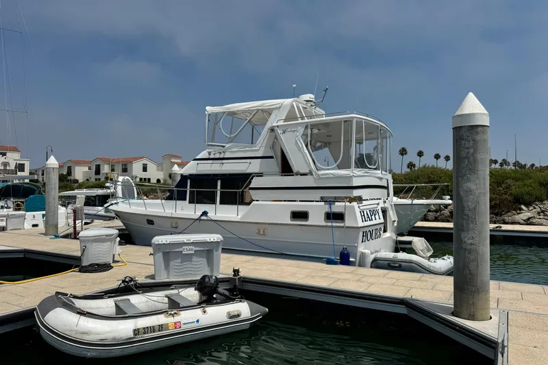 Slide: The Image of 1999 Heritage East Sundeck 36 yacht docked at marina with inflatable boat nearby. - 3