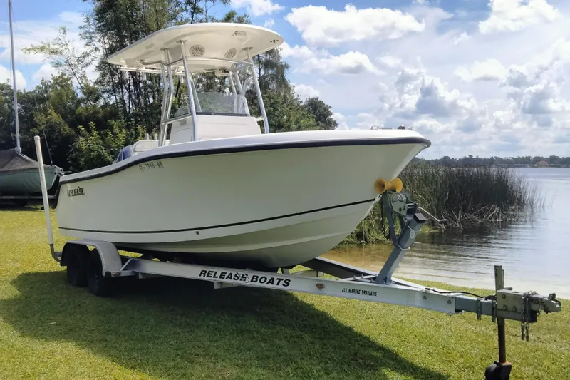 Slide: The Image of 2017 Release 208RX boat on trailer by a lake, surrounded by trees and grass. - 2