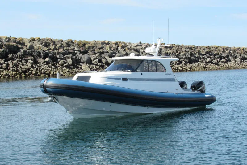 The Image of 2017 Ribcraft Express 32 boat on calm water near rocky shoreline. - 0