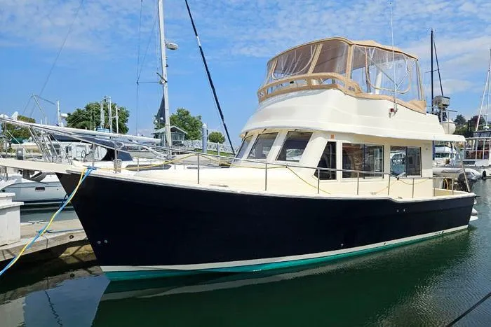 The Image of 2007 Mainship 34 Trawler docked in marina under clear blue sky. - 0