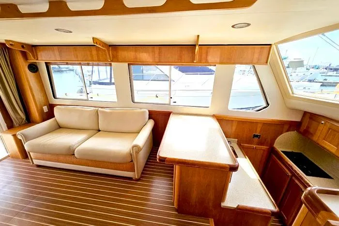 Slide: The Image of Interior of 2007 Mainship 34 Trawler with sofa, wooden cabinetry, and large windows. - 10