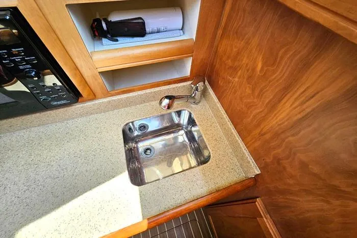 Slide: The Image of 2007 Mainship 34 Trawler kitchen sink with wooden cabinetry and countertop. - 15
