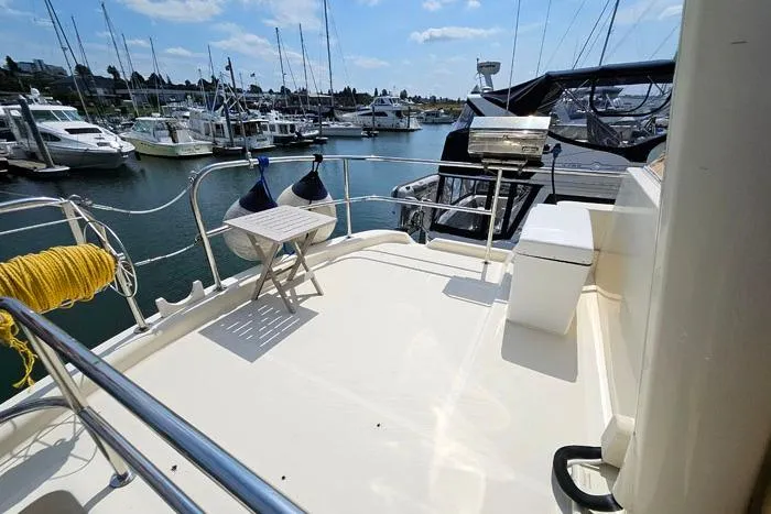 Slide: The Image of 2007 Mainship 34 Trawler deck with marina view, featuring seating and grill. - 4